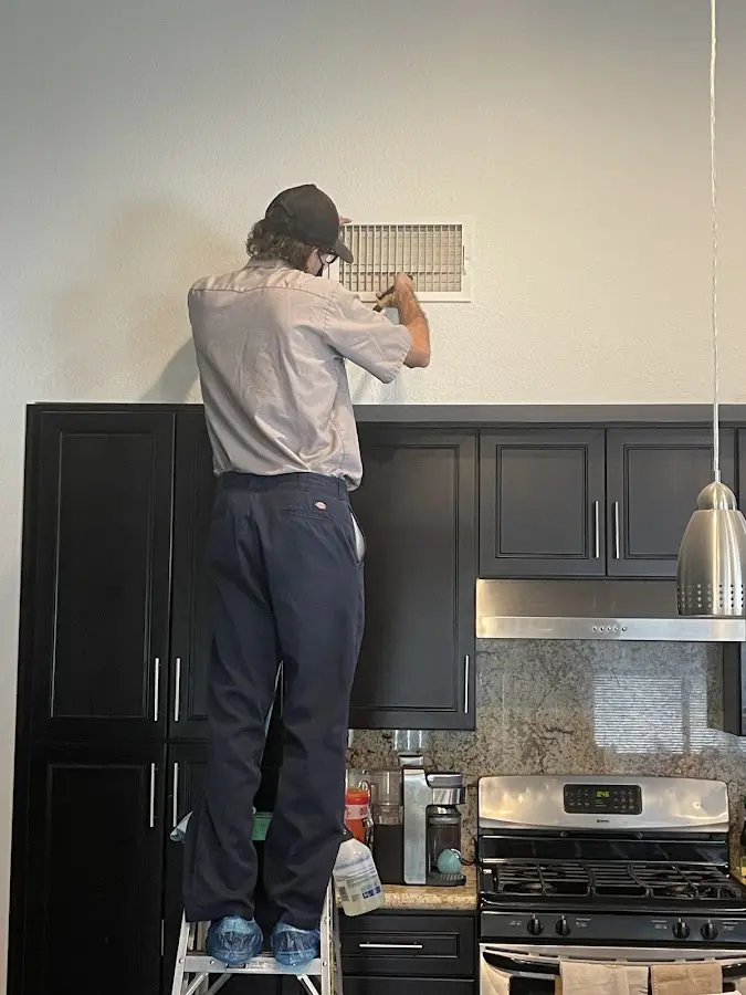 Technician inspecting an air vent during HVAC service in Holland
